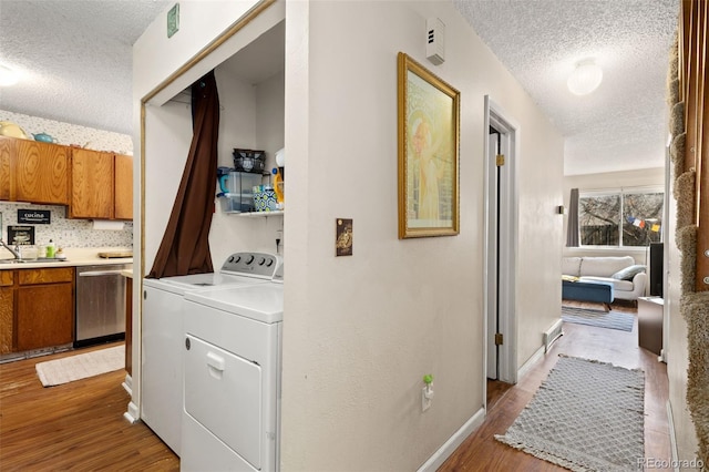 washroom featuring light wood-style flooring, a sink, a textured ceiling, separate washer and dryer, and laundry area