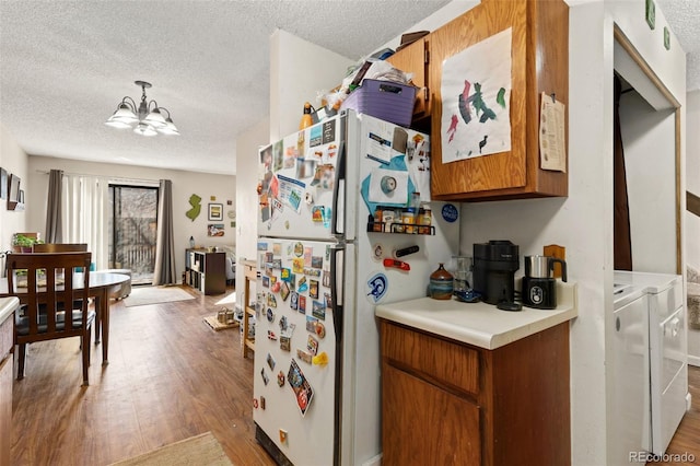 kitchen with decorative light fixtures, light countertops, brown cabinetry, freestanding refrigerator, and separate washer and dryer