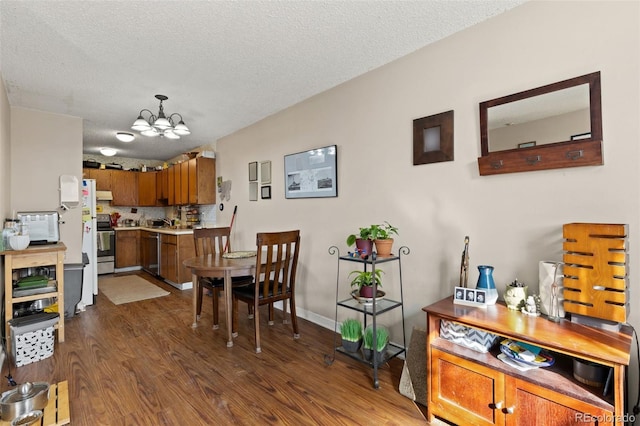 dining room featuring dark wood-style flooring, a notable chandelier, a textured ceiling, and baseboards