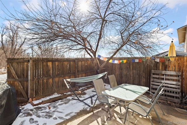 snow covered patio featuring fence, area for grilling, and outdoor dining space