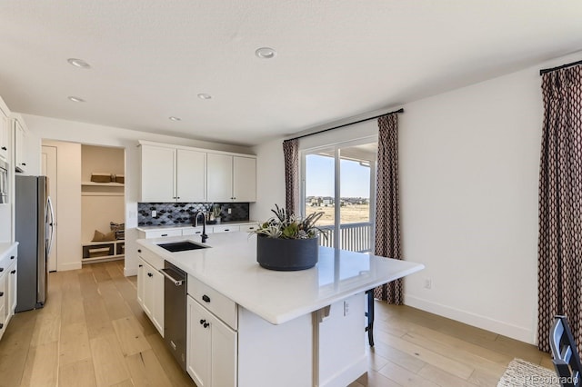 kitchen with white cabinets, appliances with stainless steel finishes, sink, and an island with sink