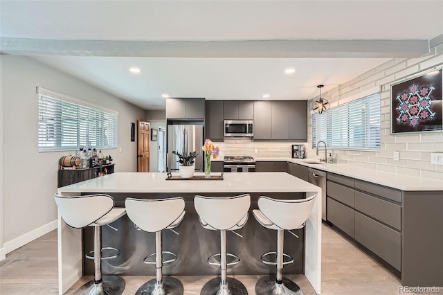 1025 Zang St, Golden, CO 80401 - kitchen with a breakfast bar area, a center island, tasteful backsplash, a sink, and stainless steel appliances