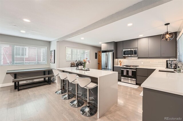 1025 Zang St, Golden, CO 80401 - kitchen featuring decorative backsplash, a kitchen island, a kitchen bar, a sink, and appliances with stainless steel finishes