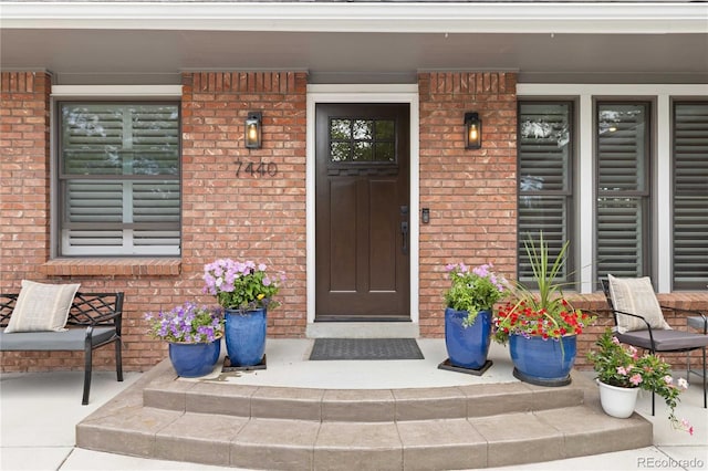 7440 Quail St, Arvada, CO 80005 - doorway to property featuring a porch and brick siding