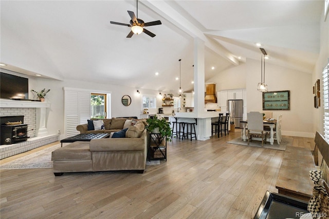 7440 Quail St, Arvada, CO 80005 - living area featuring a fireplace, beamed ceiling, ceiling fan, light wood finished floors, and high vaulted ceiling