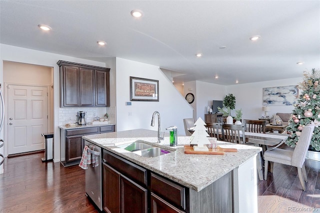 kitchen featuring light stone countertops, sink, dark hardwood / wood-style flooring, stainless steel dishwasher, and an island with sink