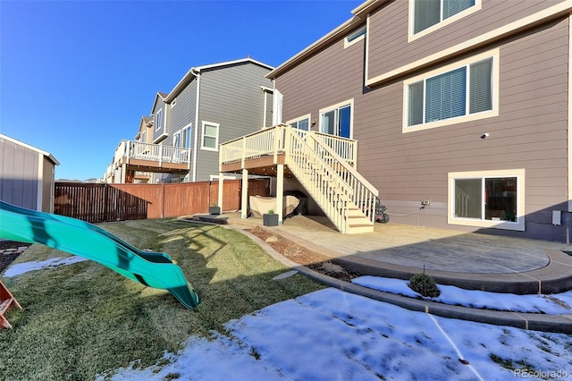 snow covered house with a playground and a wooden deck