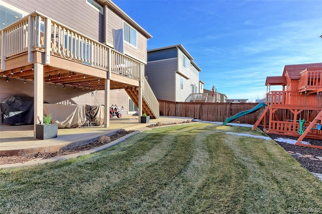 view of yard featuring a playground, a wooden deck, and a patio