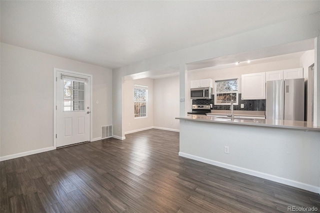 1403 Valentia St, Denver, CO 80220 - kitchen featuring stainless steel appliances, decorative backsplash, white cabinets, dark wood-type flooring, and light countertops
