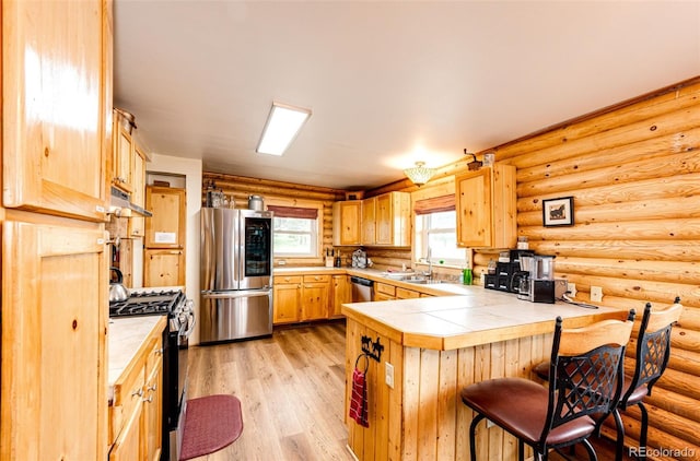 7573 Pine Crest Dr, Kiowa, CO 80117 - kitchen featuring appliances with stainless steel finishes, a peninsula, tile countertops, under cabinet range hood, and a kitchen bar