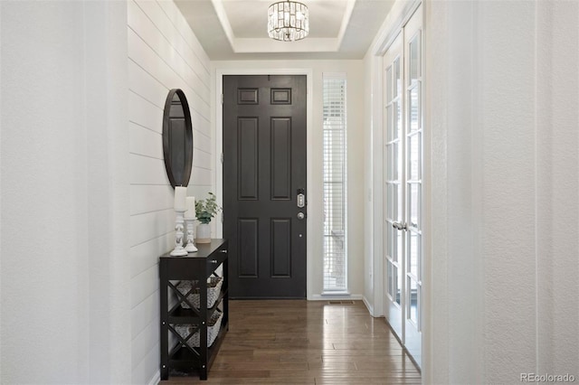 entrance foyer featuring a chandelier, dark hardwood / wood-style floors, and a raised ceiling