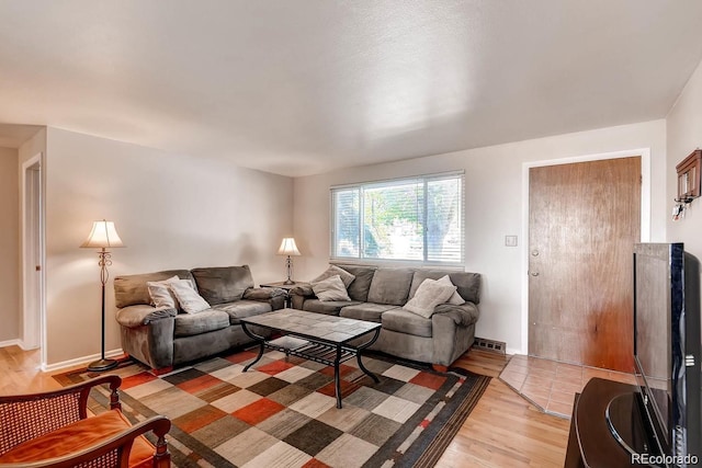 living area with light wood-style flooring, visible vents, and baseboards