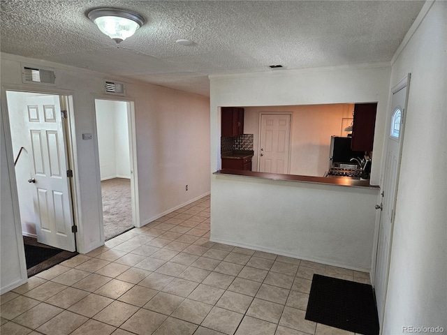 kitchen with kitchen peninsula, sink, light tile patterned flooring, and a textured ceiling