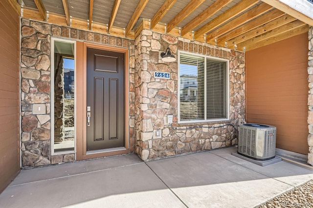 doorway to property with stone siding and central AC