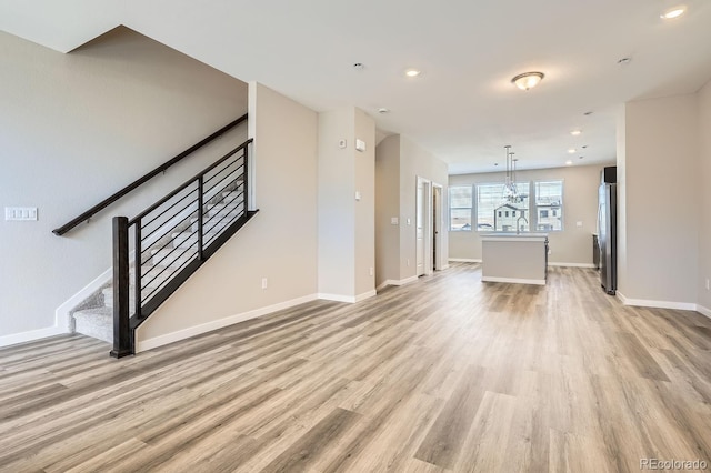 unfurnished living room with light wood finished floors, baseboards, stairway, and recessed lighting