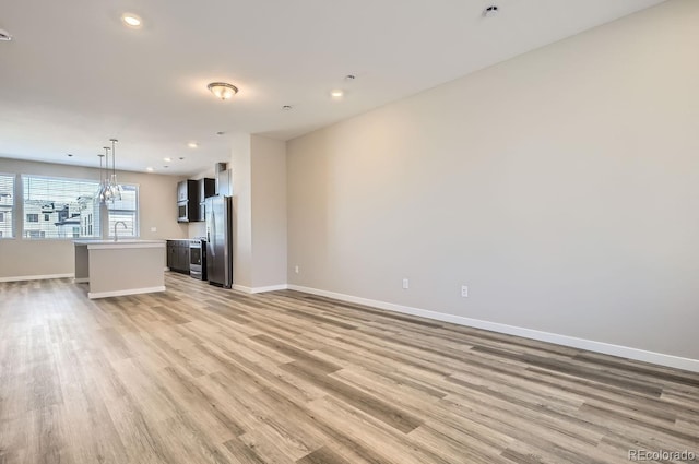 unfurnished living room with light wood-style floors, recessed lighting, and baseboards