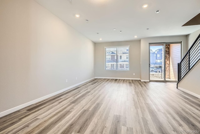 unfurnished living room with recessed lighting, light wood-style flooring, and baseboards