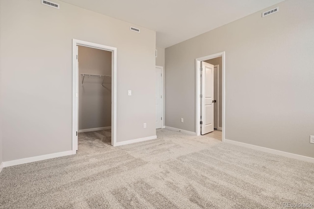 unfurnished bedroom featuring baseboards, a spacious closet, and visible vents