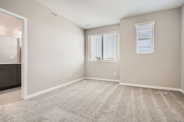 empty room featuring baseboards, visible vents, and light colored carpet