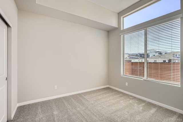 unfurnished room with carpet and baseboards