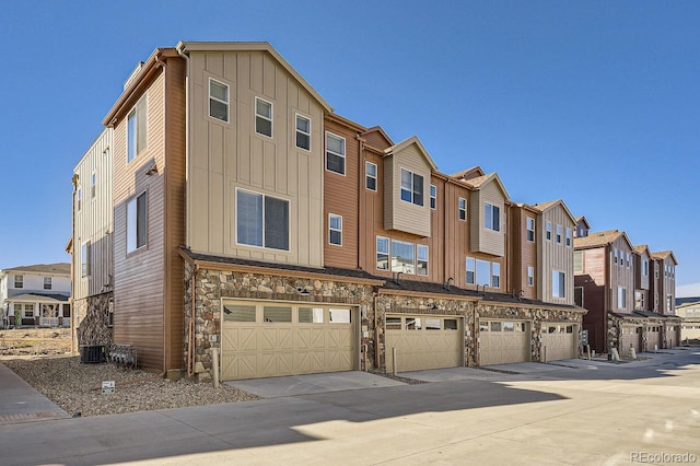 view of building exterior featuring concrete driveway, an attached garage, and a residential view