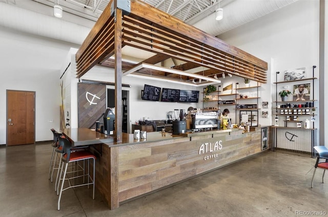 bar featuring a dry bar, concrete floors, and a towering ceiling