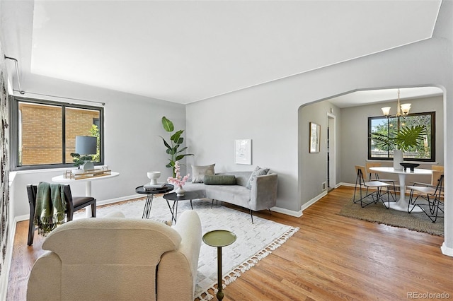 2955 Poplar St, Denver, CO 80207 - living room featuring light wood-type flooring, a chandelier, and arched walkways