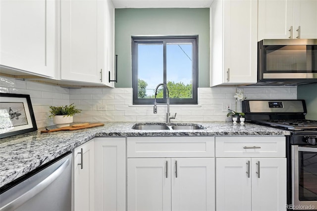 2955 Poplar St, Denver, CO 80207 - kitchen with appliances with stainless steel finishes, white cabinets, and light stone counters
