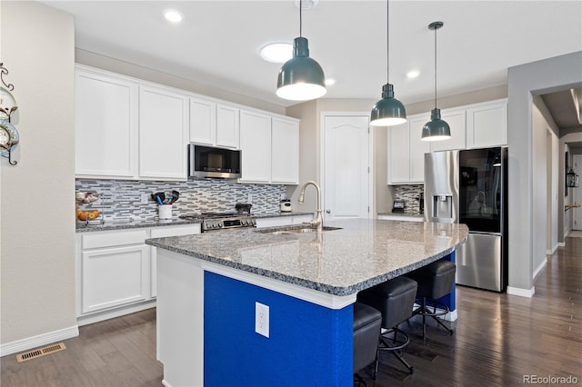 kitchen with a kitchen island with sink, dark wood-style flooring, a sink, visible vents, and appliances with stainless steel finishes