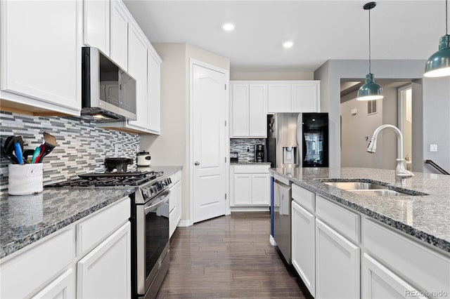 kitchen featuring dark wood-style flooring, stainless steel appliances, white cabinetry, pendant lighting, and a sink