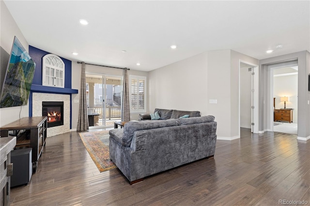 living room featuring recessed lighting, baseboards, dark wood-type flooring, and a glass covered fireplace