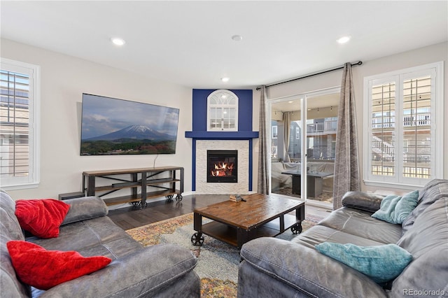 living area with a glass covered fireplace, plenty of natural light, wood finished floors, and recessed lighting