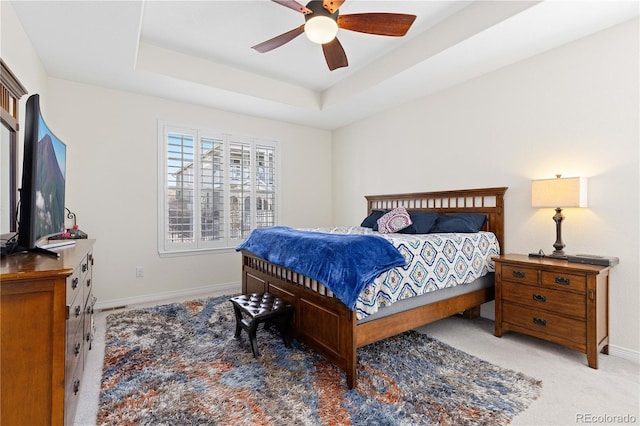 bedroom with carpet floors, baseboards, a tray ceiling, and a ceiling fan