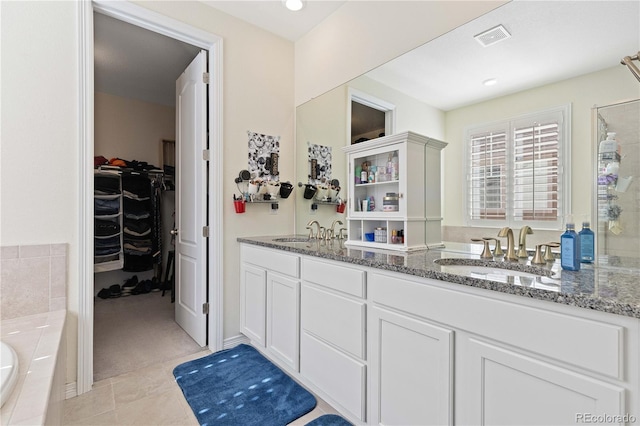 bathroom with double vanity, a sink, visible vents, and a walk in closet