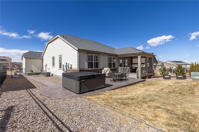 rear view of house featuring a hot tub, roof with shingles, fence, a yard, and a patio area