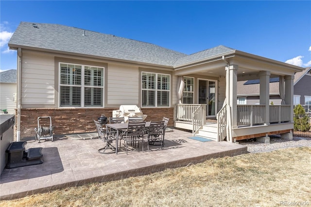 rear view of property with a shingled roof and a patio area