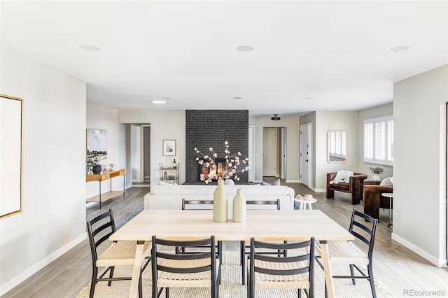 dining space featuring light hardwood / wood-style flooring and a brick fireplace