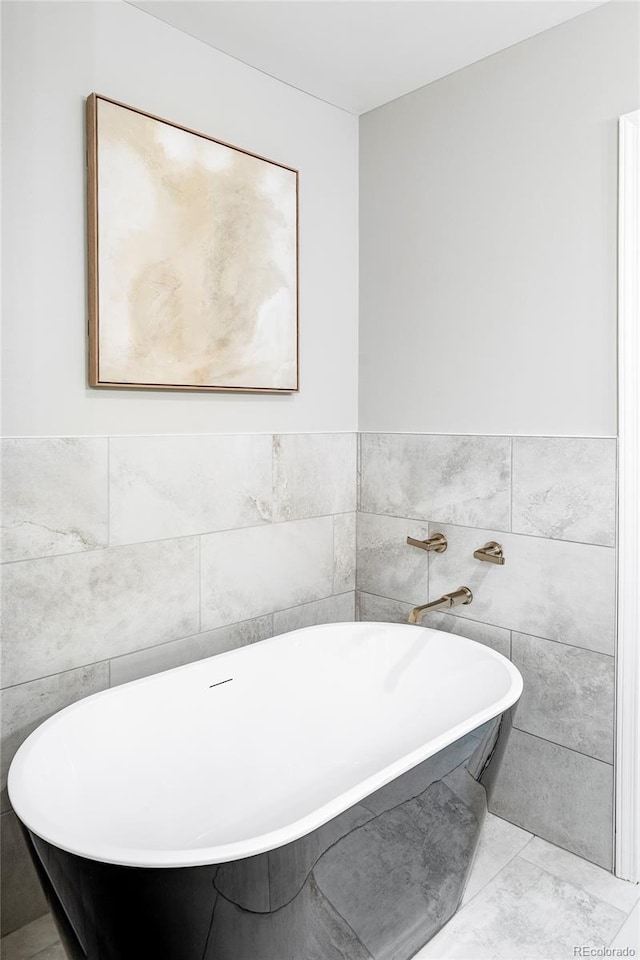 bathroom with tile patterned flooring, a bathtub, and tile walls