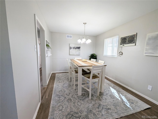 dining room featuring visible vents, baseboards, a notable chandelier, and wood finished floors