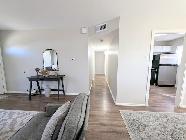 corridor featuring visible vents, baseboards, and wood finished floors