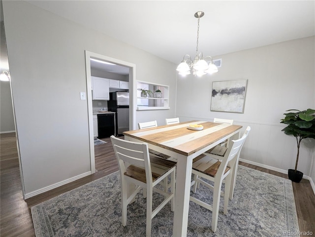 dining space with dark wood finished floors, a notable chandelier, wainscoting, and visible vents