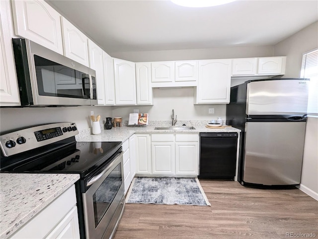 kitchen featuring appliances with stainless steel finishes, white cabinetry, light wood-style floors, and a sink