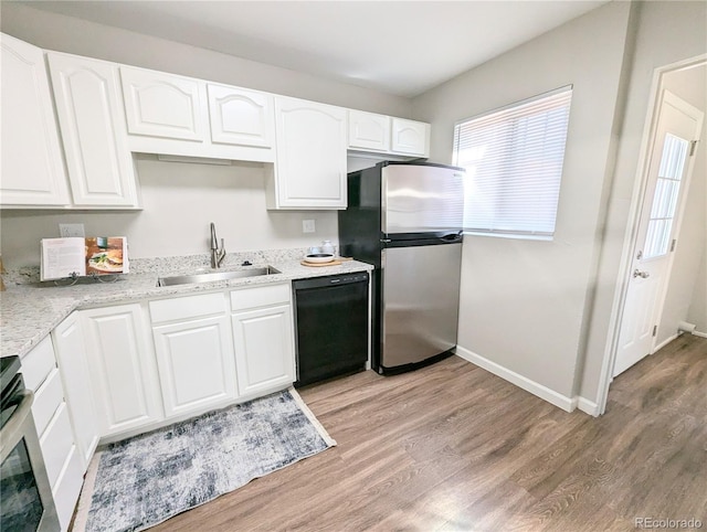 kitchen with a healthy amount of sunlight, freestanding refrigerator, black dishwasher, and a sink