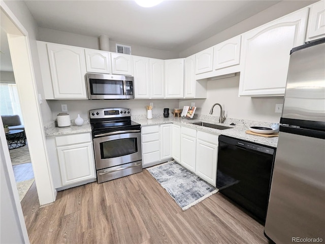 kitchen with light wood-type flooring, visible vents, a sink, stainless steel appliances, and white cabinets