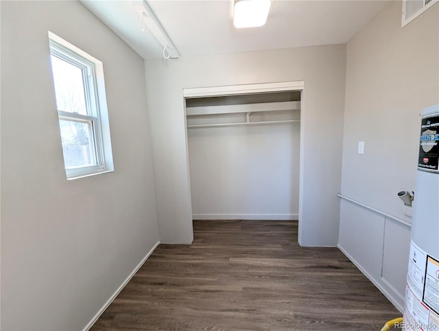 unfurnished bedroom featuring a closet, visible vents, baseboards, and dark wood-style flooring