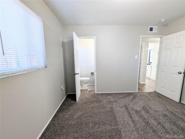 unfurnished bedroom featuring carpet flooring, baseboards, visible vents, and connected bathroom