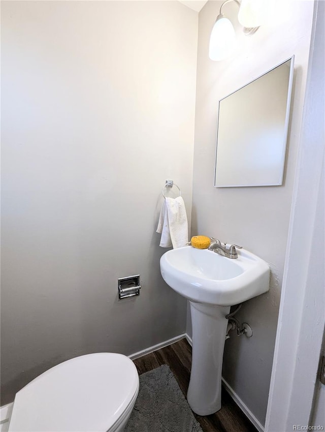 bathroom with toilet, wood finished floors, and baseboards