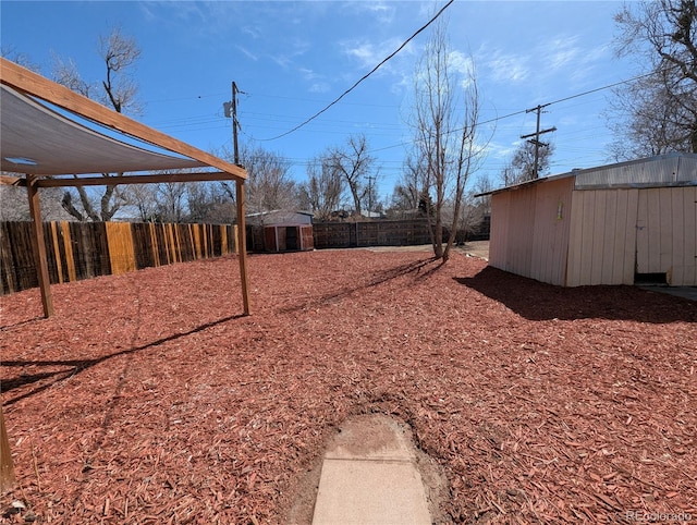 view of yard with a storage shed, a fenced backyard, and an outdoor structure