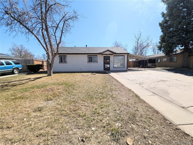 ranch-style house featuring an attached carport, a front lawn, concrete driveway, and fence