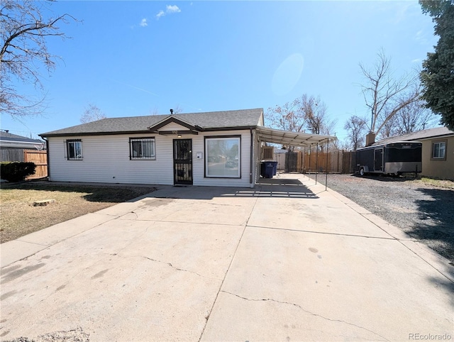 view of front of house with a carport, concrete driveway, and fence